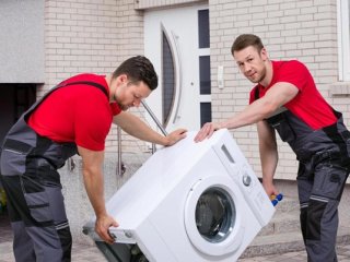 dwóch mężczyzn przenosi pralkę