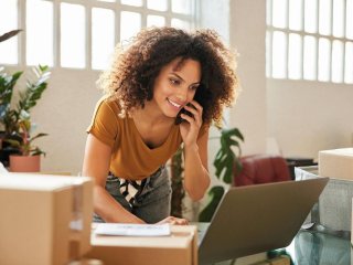 kobieta rozmawia przez telefon i patrzy na ekran laptopa